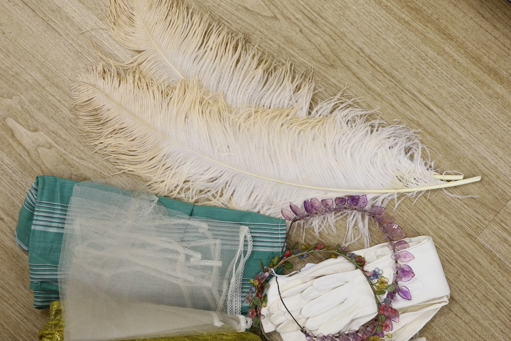 Two 1920's floral bead headdresses, a baby dress, gold fabric, two feathers and three prs of gloves